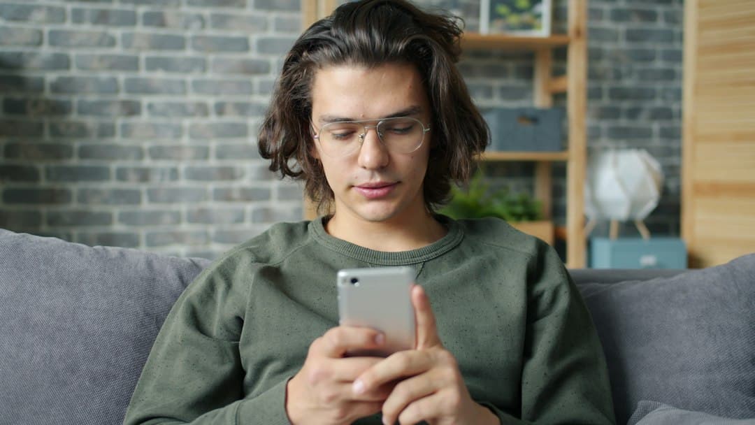 Iemand op de bank met een smartphone in de hand, een IPTV-abonnement kopen bij Nero IPTV